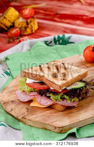 New Years Sandwich With Sausage, Tomatoes, Cheese, Sauce And Lettuce On A Wooden Board. Against The 