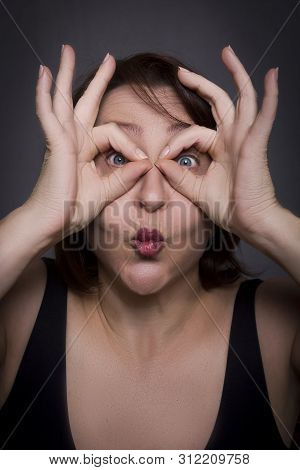 Woman Grimaces In Front Of Camera On Black Background