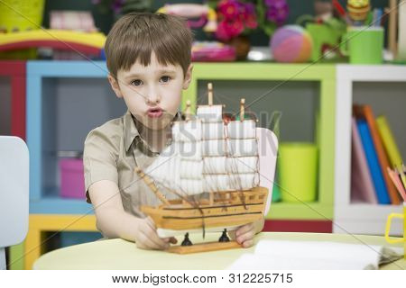 Boy Playing With Ship.child With A Toy Sailboat
