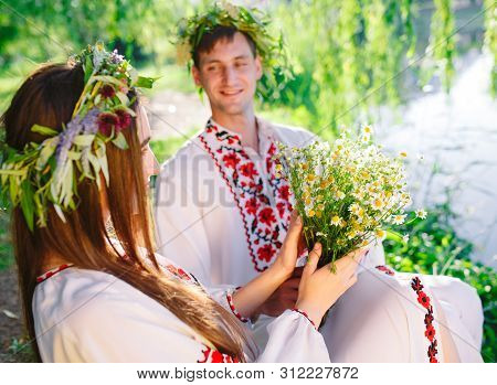 Midsummer. Young Loving Couple In Slavic Costumes On The Shore Of The Lake. Slavonic Holiday Of Ivan