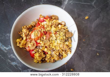 Muesli With Chocolate And Fresh Strawberries In A Plate On A Dark Gray Background. The Concept Of He