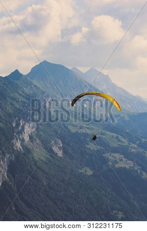 Vertical Photography Of Tandem Paragliding In Interlaken, Switzerland In Bad Weather. Flying Over Sw