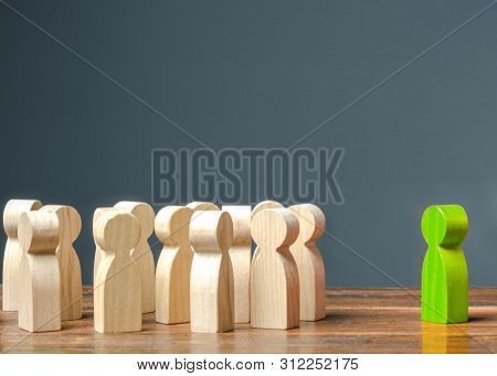Green Figurine Of A Man Stands Near The Crowd Of People. Development Of Leadership And Social Qualit