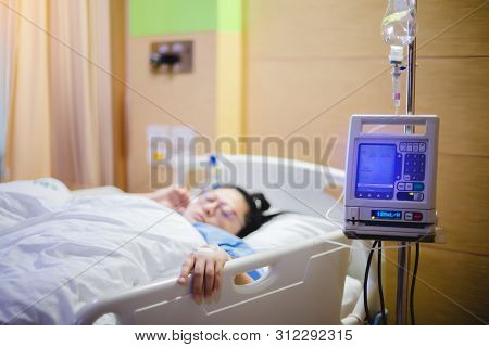 Selective Focus To Hand Of Patient Draw To Infusion Pumps And Saline Bag In Hospital. Blurry Infusio