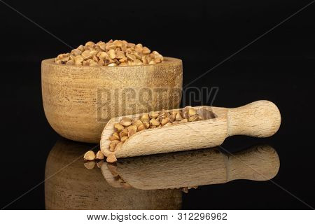 Lot Of Whole Raw Brown Buckwheat Grain In A Wooden Bowl With Wooden Scoop Isolated On Black Glass