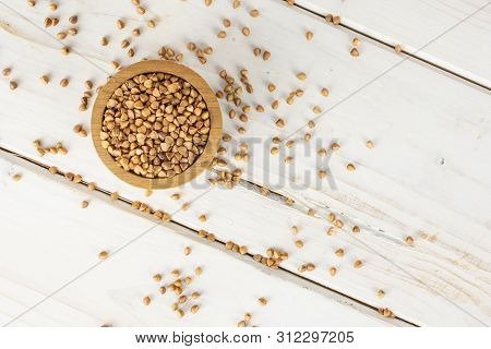 Lot Of Whole Raw Brown Buckwheat Grain In A Wooden Bowl Flatlay On White Wood