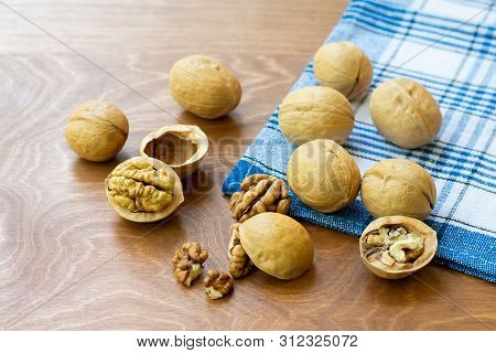 Whole Walnuts And Walnut Kernel Halves Without Shell On A Dark Wooden Table And Checkered Towel, Clo