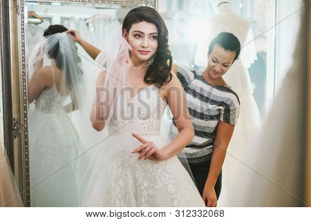 Beautifu bride choosing wedding dress in a wedding salon