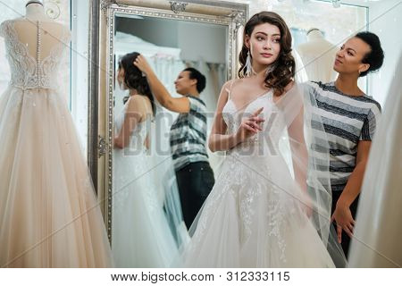 Beautifu bride choosing wedding dress in a wedding salon