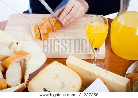 Table With Food And Female Hands Cutting Bread