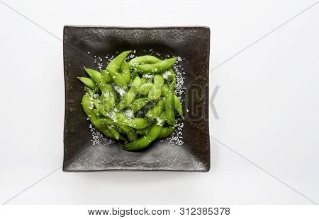 Edamame Green Soybeans In The Bowl, Fried Green Soybeans With Salt In A Black Bowl On White Backgrou