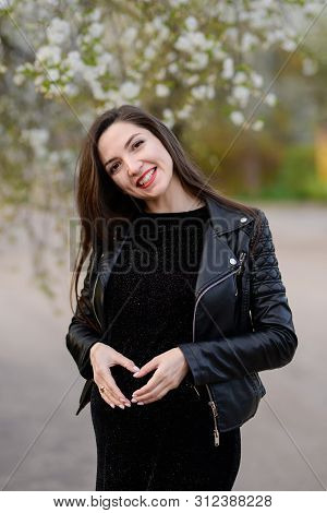 The Girl Shows The Heart On The Belly Of A Pregnant Woman. Beautiful Pregnant Woman Loves A Child, M