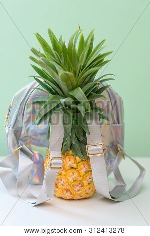 Pineapple With Holographic Bag On White Wooden Table Over Neo Mint Background. Tropical Summer Vacat