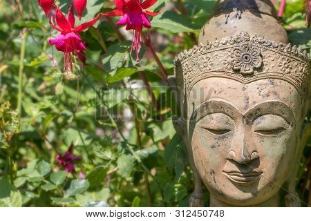 Serene Buddha Face. Garden Statue With Fuschia Flowers. Buddhism At One With Nature. Natural World I