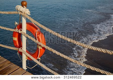 On The Beach There Is A Rescue Tool For Drowning People In The Form Of A Life Buoy With A Rope