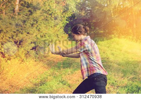 Girl In Colorful Shirt Focusing And Practicing Tai Chi In The Nature Outdoor In A Sunny Warm Summer 