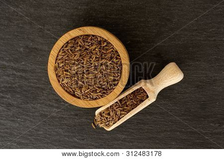 Lot Of Whole Dry Caraway Fruits In A Wooden Bowl With Wooden Scoop Flatlay On Grey Stone