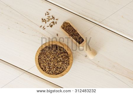 Lot Of Whole Dry Caraway Fruits In A Wooden Bowl With Wooden Scoop Flatlay On White Wood