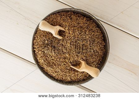 Lot Of Whole Dry Caraway Fruits In A Grey Ceramic Bowl With Wooden Scoop Flatlay On White Wood