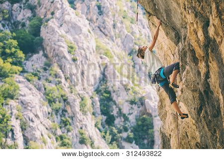 Rock Climbing And Mountaineering In The Paklenica National Park. A Woman Overcomes A Challenging Cli