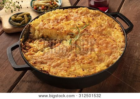 Shepherds Pie With Pickles, Herbs, And Red Wine On A Dark Rustic Wooden Background
