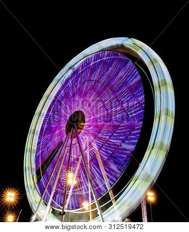Spinning Ferris Wheel At Night In A Park Of Distractions With Beautiful Colors.