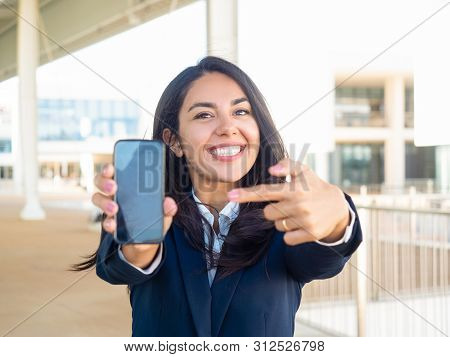 Happy Satisfied Businesswoman Advertising Online Mobile App. Beautiful Young Woman In Office Suit Sh
