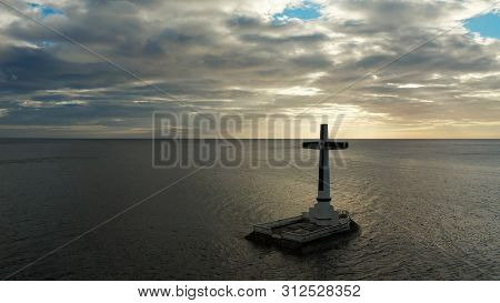 Catholic Cross In Sunken Cemetery In The Sea At Sunset, Aerial Drone. Large Crucafix Marking The Und