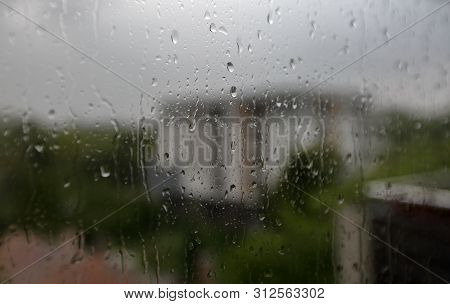 Raindrops On Wondow Glass Viewed From Interior, Close Up, Rainy Weather, In Background Grey Sky, Tre