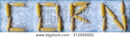 Corn Word Made With Shucked Raw Corns. Corn Text Made With Corn On Bright Blue Background