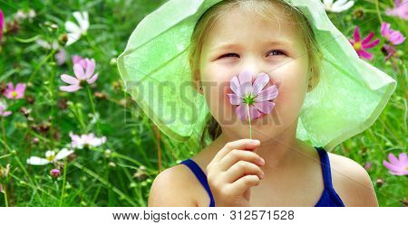 Child Sniffing Flower. Girl With A Flower In Her Hand. Child Among The Flowers. Pollen Allergy