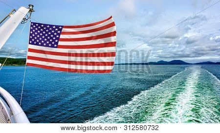 American Flag Flying Over The Blue Waters.
