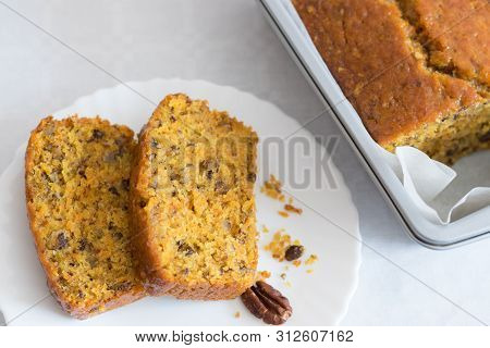 Two Pieces Of Carrot Cake With Pecans On A White Plate