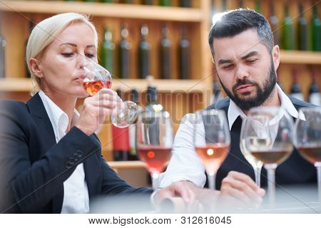 Male and female cavists working with samples of new sorts of wine