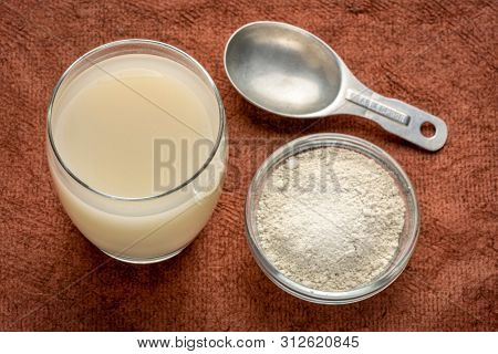 food grade diatomaceous earth supplement - powder and in a glass of water  with measuring scoop