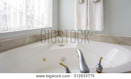 Panorama Bathroom Interior With Agleaming Bathtub Beside A Large Arched Window