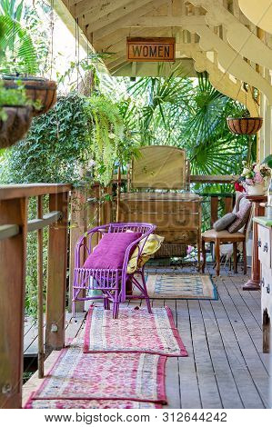 An Old Timber Verandah From Yesteryear Filled With Vintage Furniture Of A Bygone Era