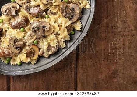 Mushroom Pasta. Farfalle With Cremini And Green Peas, Overhead Shot On A Dark Rustic Wooden Backgrou