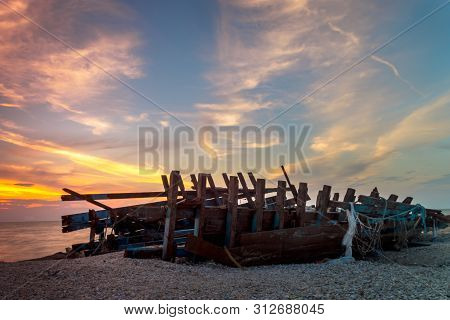 Ruin Shipwreck Golden Sunset At Beachside With Cloudy Sky