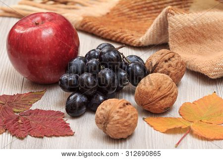 Walnuts, Grapes, Checkered Plaid And Dry Leaves On Wooden Boards. An Autumn Still Llife.