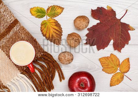 Checkered Plaid, Dry Yellow And Brown Leaves, Cup Of Coffee, Apple And Walnuts On Wooden Background.