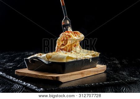 Piece Of Tasty Hot Lasagna. Traditional Italian Lasagna On A Cast Iron Pan.