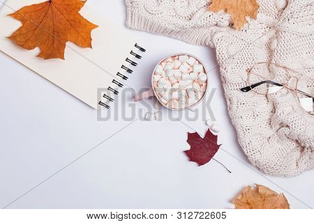 Creative Autumn Composition With Warm Knitted Sweater, Yllow Leaves And Cocoa With Marshmllows