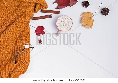 Creative Autumn Composition With Warm Knitted Sweater, Yllow Leaves And Cocoa With Marshmllows
