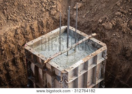 Pouring Concrete Into Steel Box For Foundation Pillar In Process Of House Building