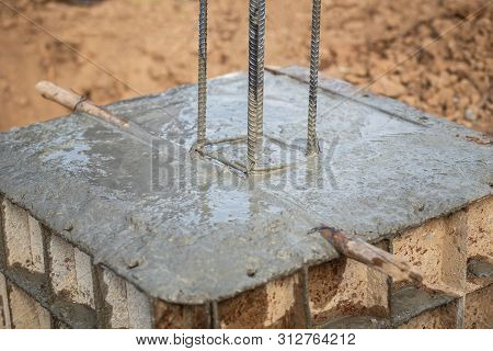 Pouring Concrete Into Steel Box For Foundation Pillar In Process Of House Building