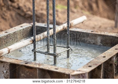 Pouring Concrete Into Steel Box For Foundation Pillar In Process Of House Building