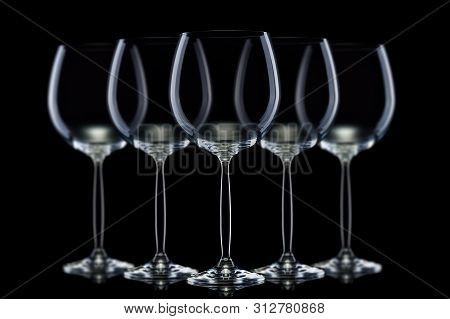 Set Of Mpty Glasses For Red Wine In A Row Isolated On Black Background.