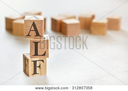 Three Wooden Cubes With Letters Alf Means Always Listen First , On White Table, More In Background, 