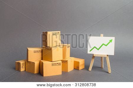 Plenty Of Cardboard Boxes And Whiteboard With Green Positive Chart Arrow Up. Increasing Consumer Dem